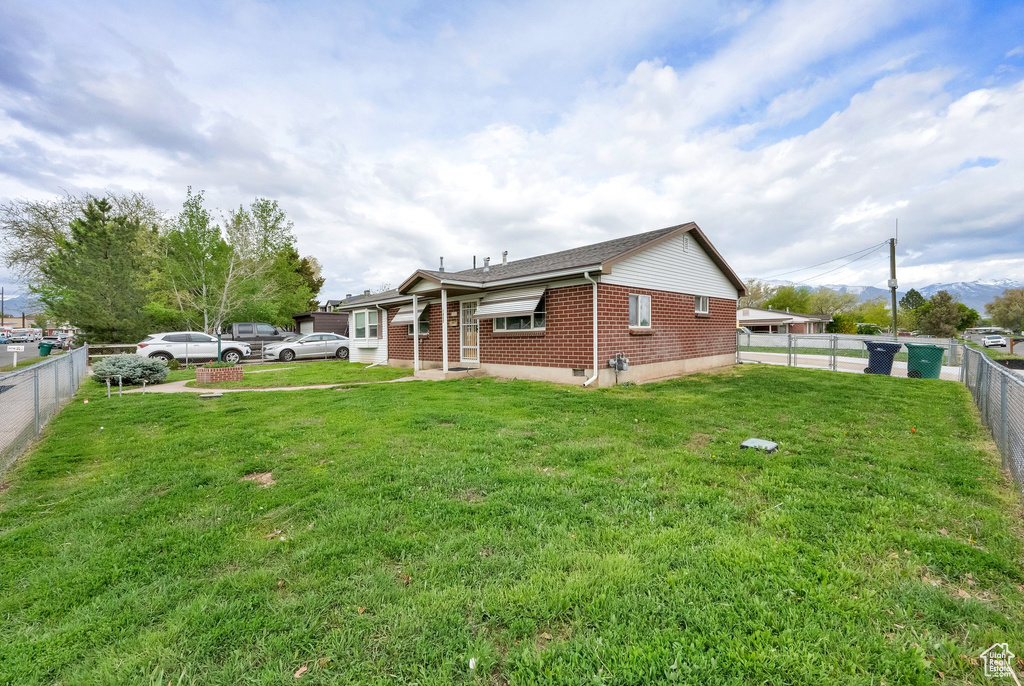 Exterior space featuring brick siding, a fenced backyard, and a yard