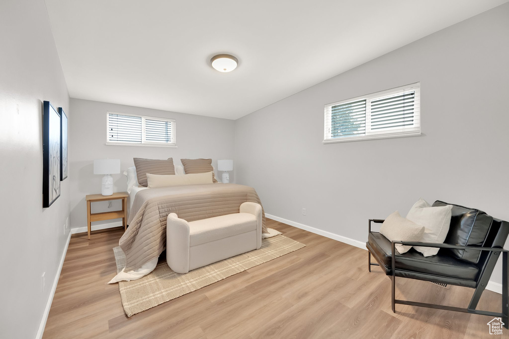 Bedroom featuring baseboards, multiple windows, and light wood-style flooring