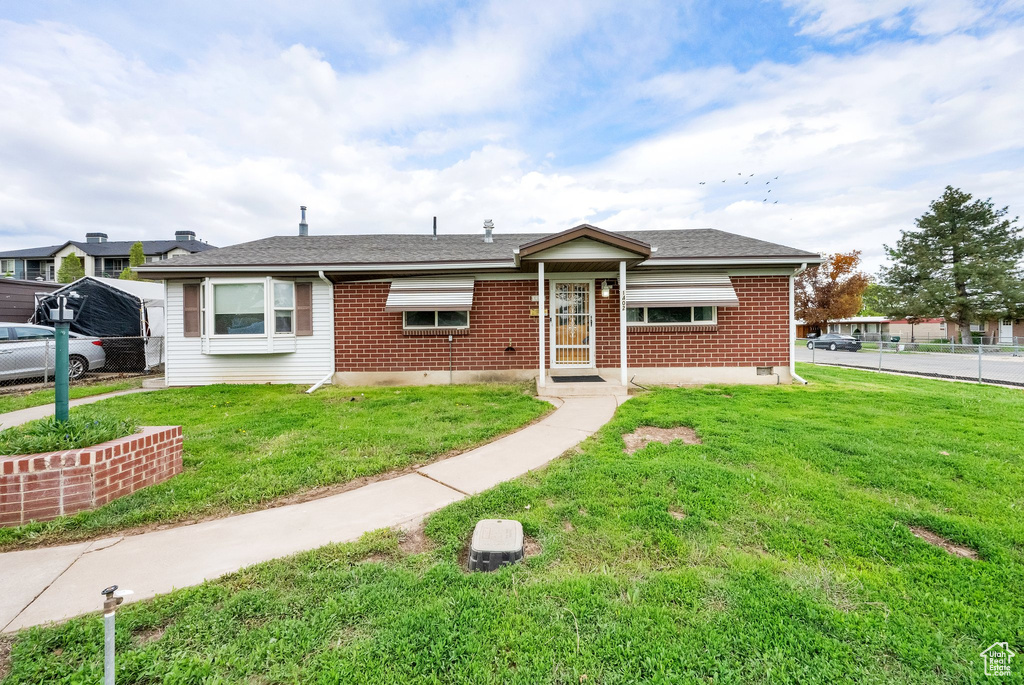 View of front of house with fence, a front yard, and brick siding