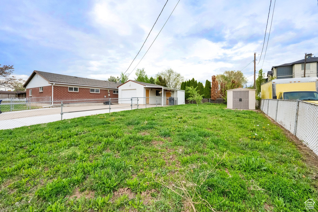View of yard with a shed, an outdoor structure, a fenced backyard, and a garage