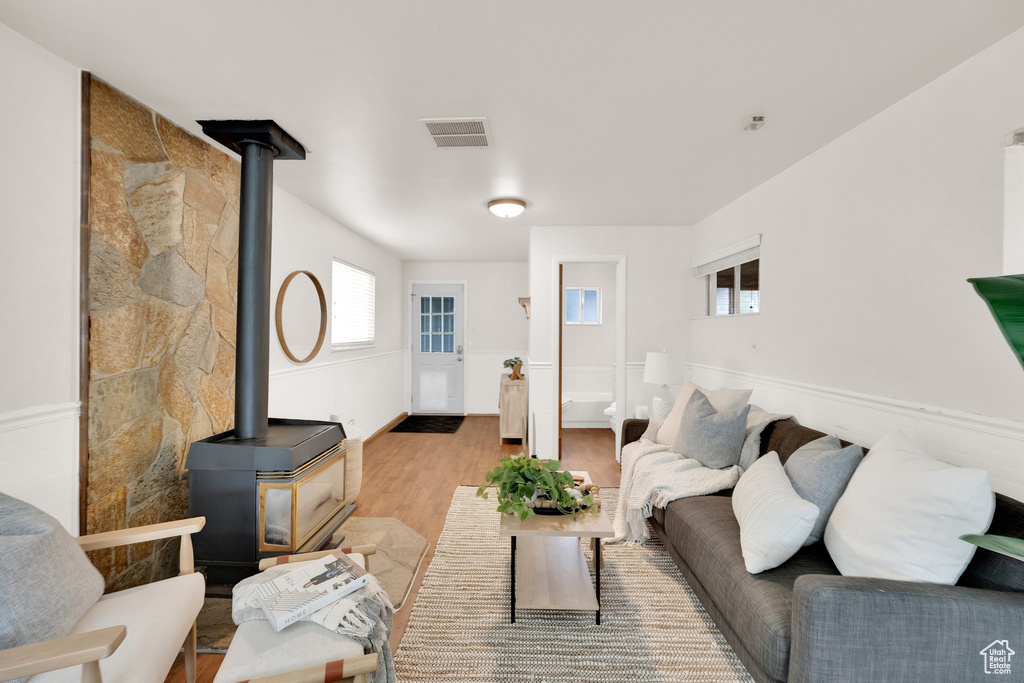 Living room featuring visible vents, a wood stove, plenty of natural light, and wood finished floors