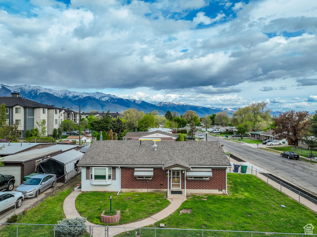 View of front of house featuring a shingled roof, a mountain view, and a fenced front yard