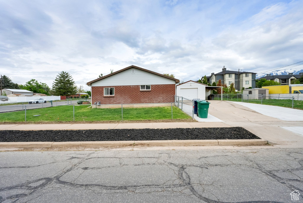 View of front of house with a front yard, fence private yard, a detached garage, brick siding, and concrete driveway