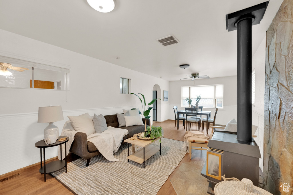 Living room featuring arched walkways, ceiling fan, visible vents, and a wood stove