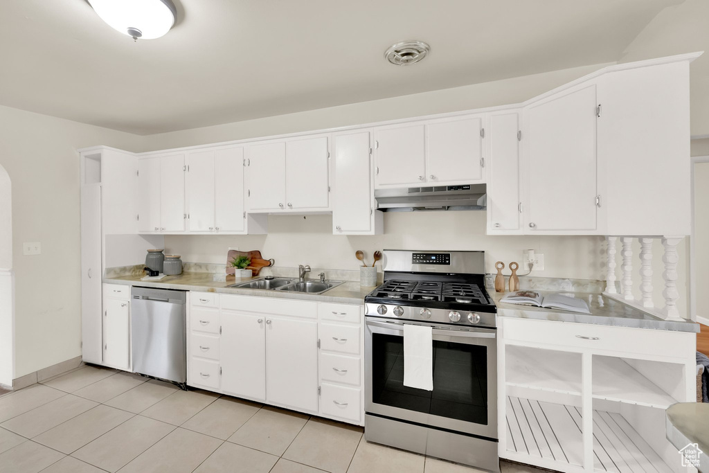 Kitchen featuring appliances with stainless steel finishes, a sink, light countertops, under cabinet range hood, and white cabinetry