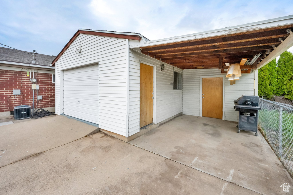 Garage featuring central air condition unit, fence, and driveway