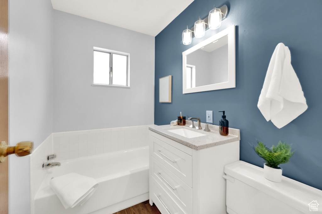 Full bath with toilet, a garden tub, and vanity