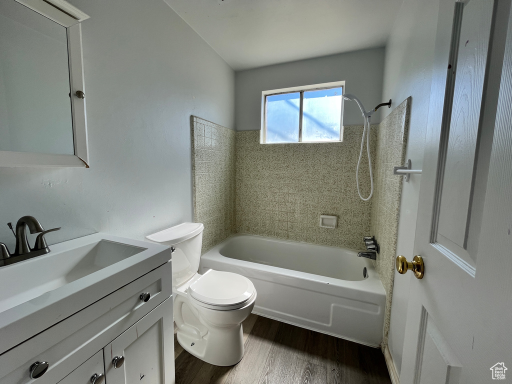 Full bath with vanity, toilet, wood finished floors, and shower / tub combination