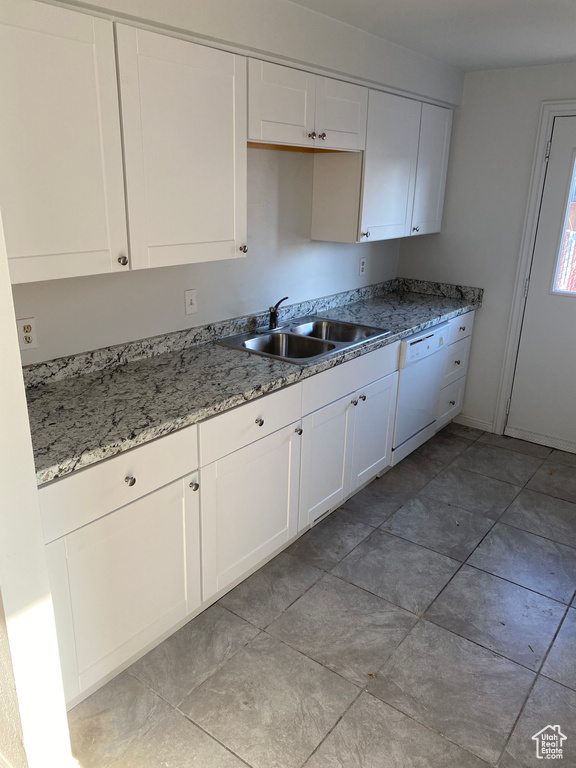 Kitchen featuring white cabinets, white dishwasher, light stone countertops, and a sink