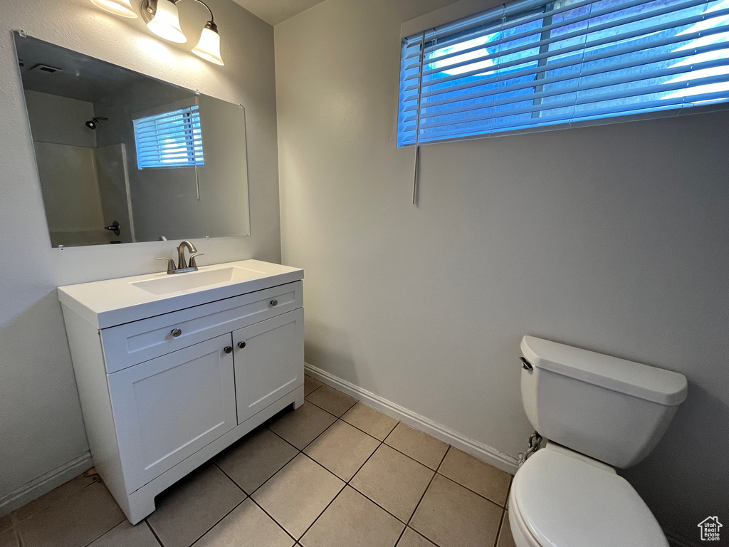 Bathroom with vanity, a shower, toilet, baseboards, and tile patterned floors