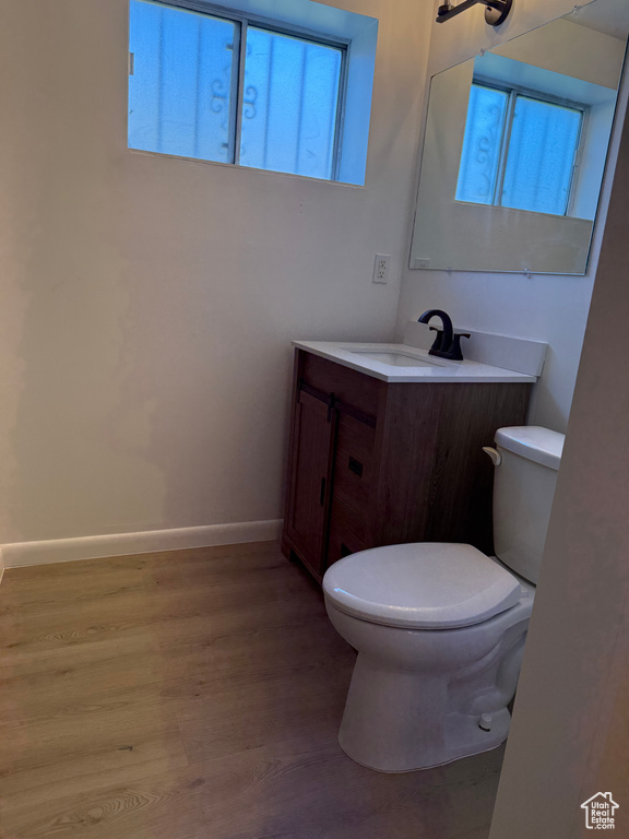Bathroom featuring baseboards, wood finished floors, toilet, and vanity