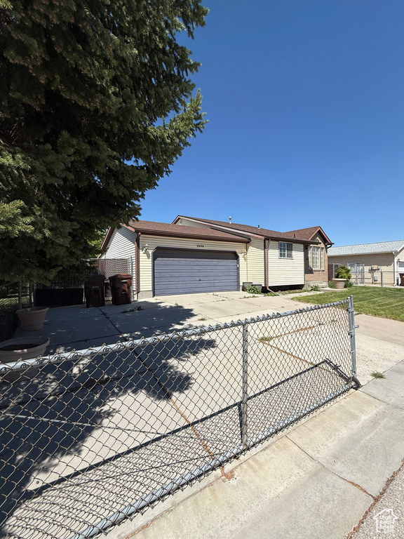 Ranch-style home featuring concrete driveway, an attached garage, and fence