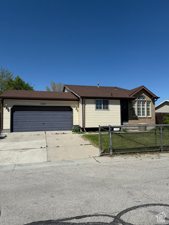 Ranch-style home with an attached garage, a fenced front yard, and concrete driveway