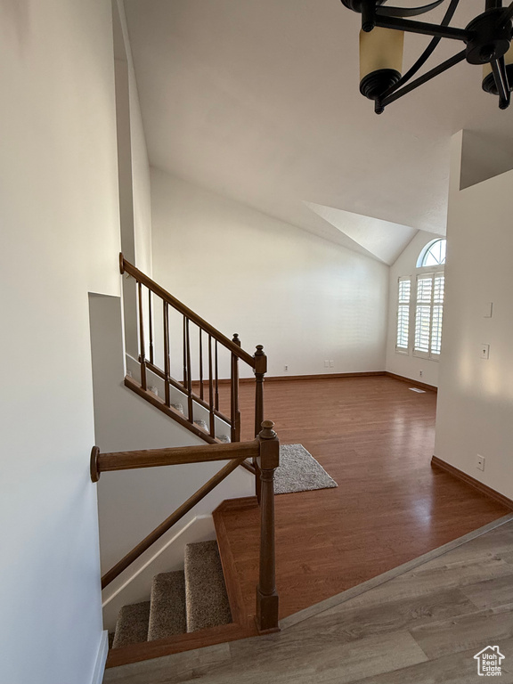 Stairway featuring baseboards, vaulted ceiling, and wood finished floors