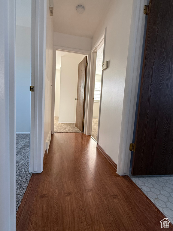 Hall featuring baseboards, visible vents, and wood finished floors