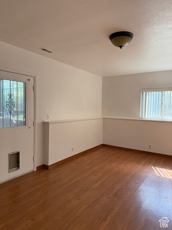 Unfurnished room featuring baseboards, wood finished floors, and visible vents