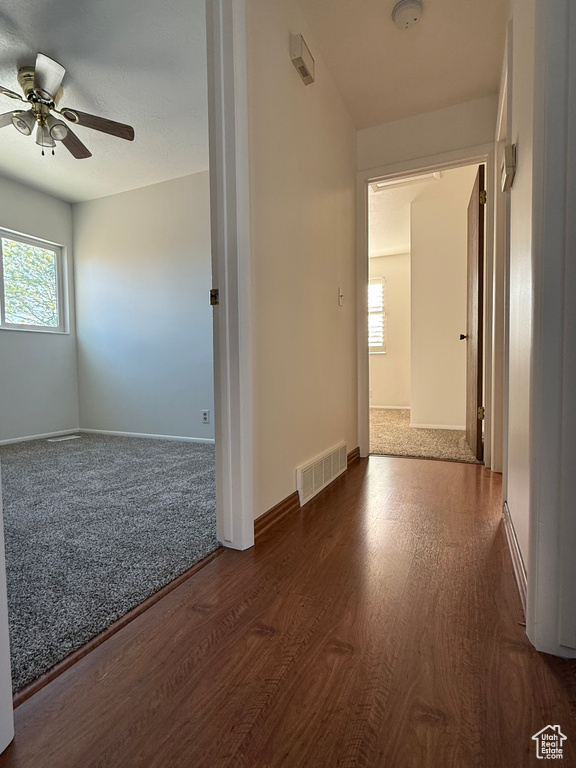 Unfurnished room featuring a ceiling fan, baseboards, visible vents, and wood finished floors