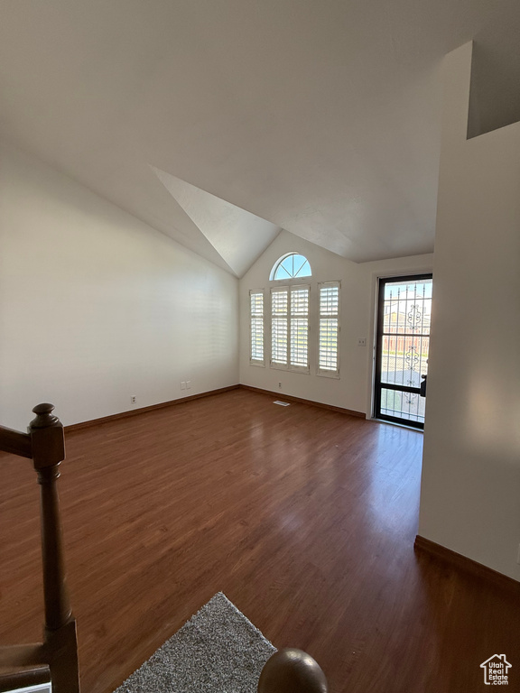 Unfurnished living room featuring baseboards, lofted ceiling, and wood finished floors