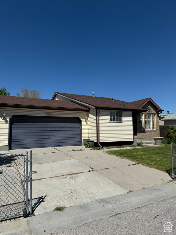 Ranch-style home featuring concrete driveway, an attached garage, fence, and a front yard