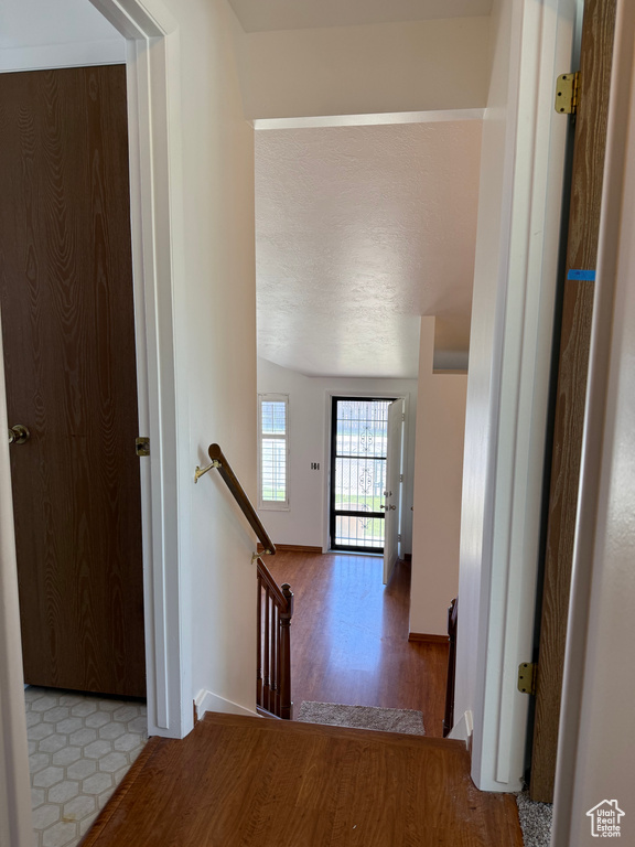 Hall with baseboards, wood finished floors, and an upstairs landing