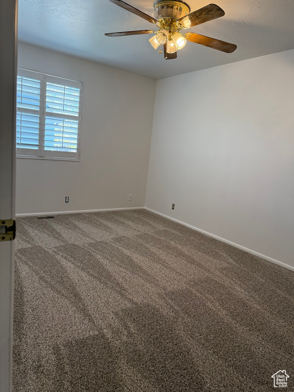 Carpeted empty room with baseboards and ceiling fan