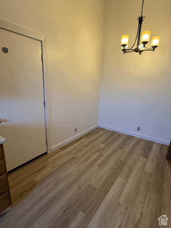 Unfurnished dining area featuring baseboards, a notable chandelier, and wood finished floors