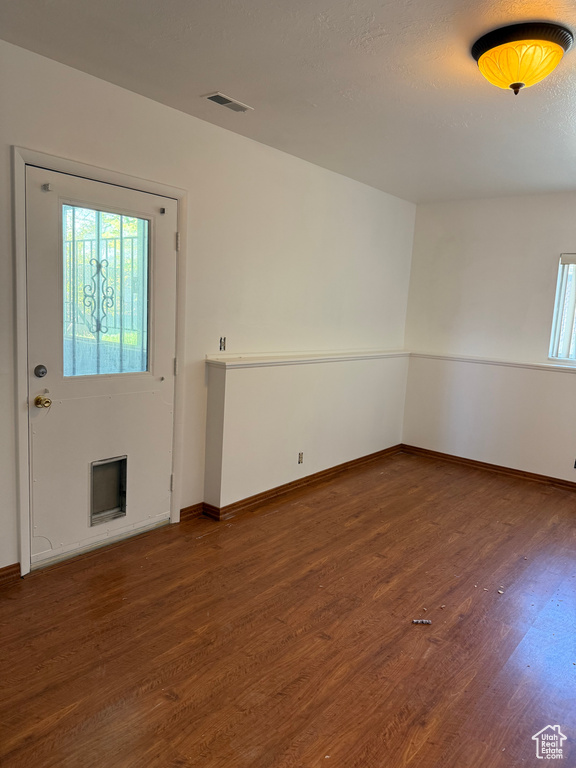 Unfurnished room featuring baseboards, wood finished floors, and visible vents