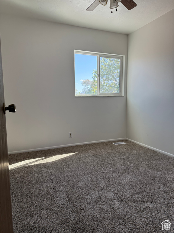 Carpeted empty room with baseboards and a ceiling fan