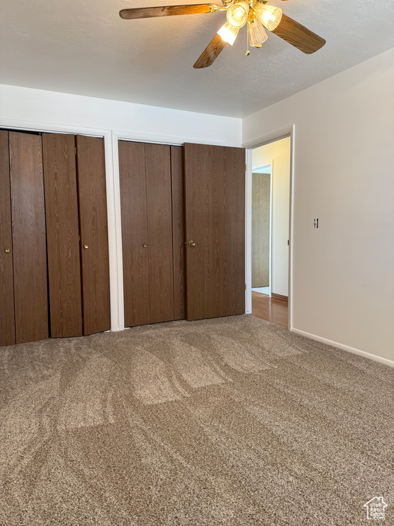 Bedroom featuring baseboards, a ceiling fan, two closets, and carpet flooring