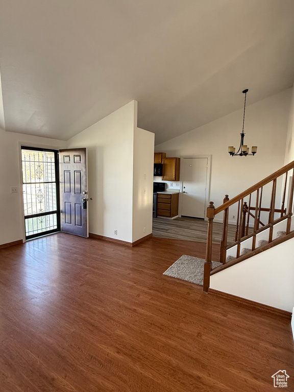 Unfurnished living room with baseboards, a notable chandelier, and vaulted ceiling
