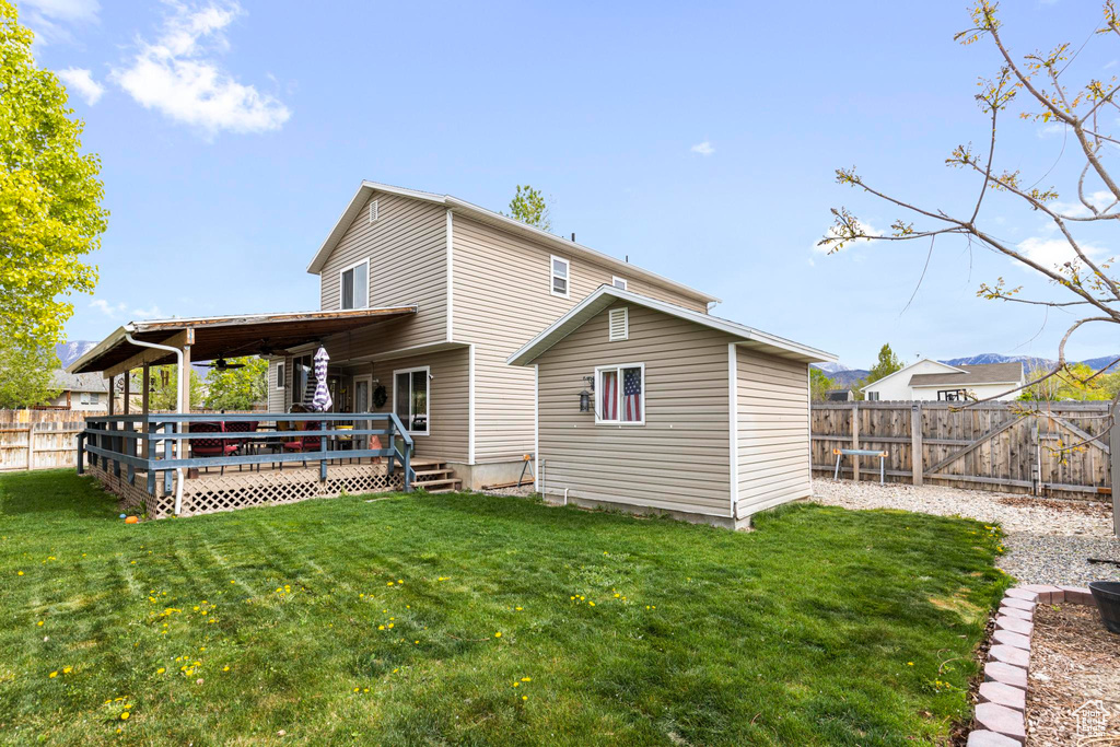 Rear view of house with a lawn, a fenced backyard, and a wooden deck