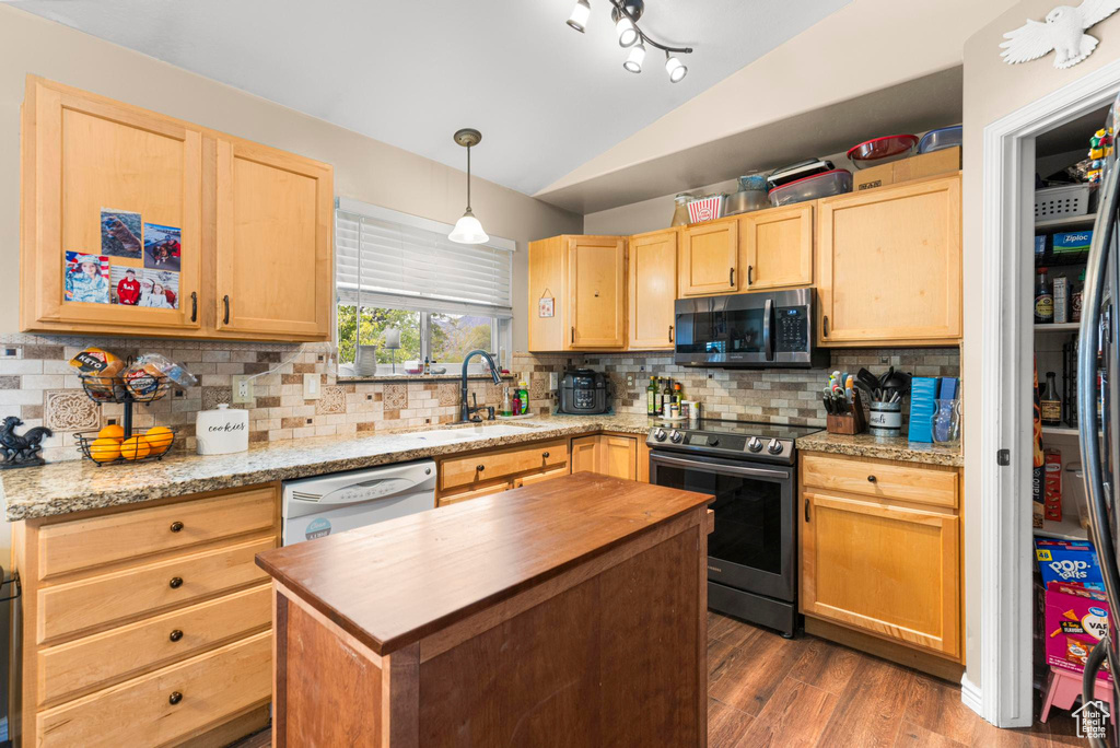 Kitchen with light brown cabinetry, appliances with stainless steel finishes, butcher block counters, and vaulted ceiling