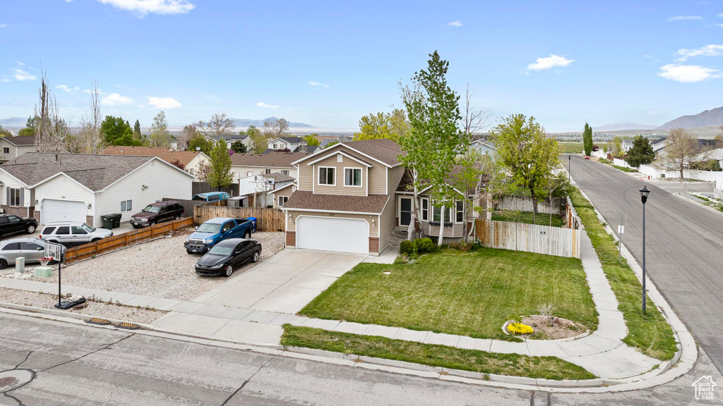 Traditional-style house with an attached garage, fence, driveway, and a residential view