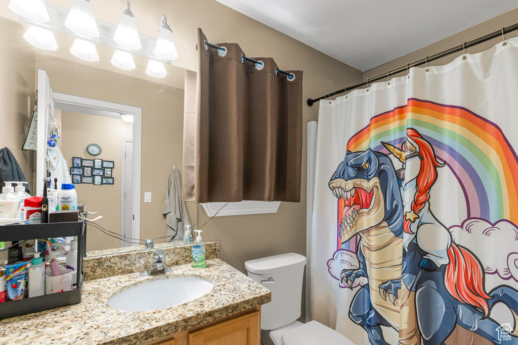 Full bath featuring toilet, a shower with shower curtain, and vanity