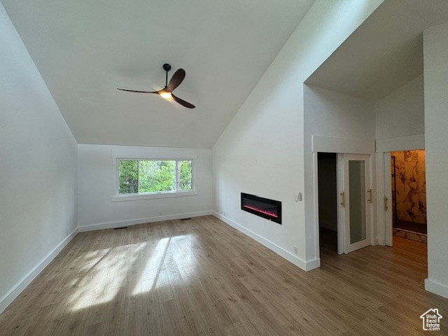 Bonus room with a glass covered fireplace, a ceiling fan, baseboards, wood finished floors, and lofted ceiling