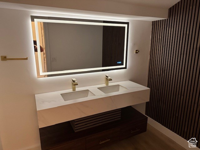 Bathroom with a sink, double vanity, and wood finished floors