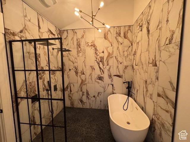 Bathroom featuring a walk in shower, lofted ceiling, a freestanding bath, and tile walls