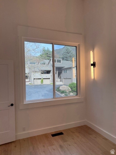 Unfurnished room with baseboards, visible vents, and light wood-type flooring