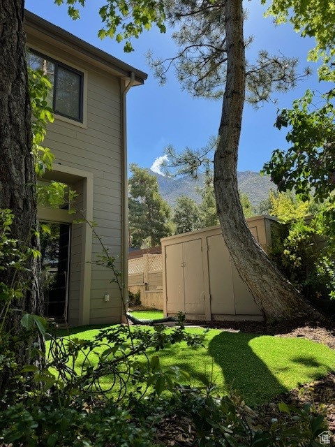 View of yard featuring a storage shed, fence, and an outdoor structure