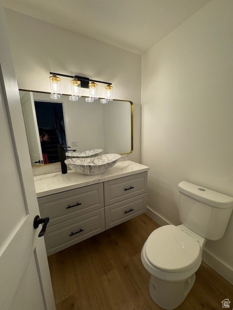 Bathroom with vanity, baseboards, wood finished floors, and toilet