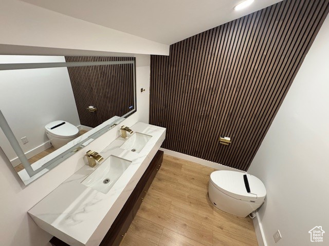 Bathroom featuring baseboards, vanity, toilet, and wood finished floors