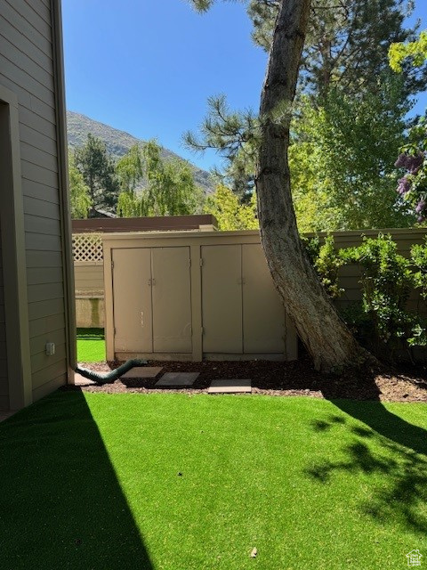 View of yard with a mountain view, fence, and a storage shed