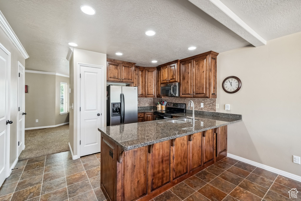 Kitchen featuring stainless steel appliances, a peninsula, baseboards, brown cabinets, and a textured ceiling