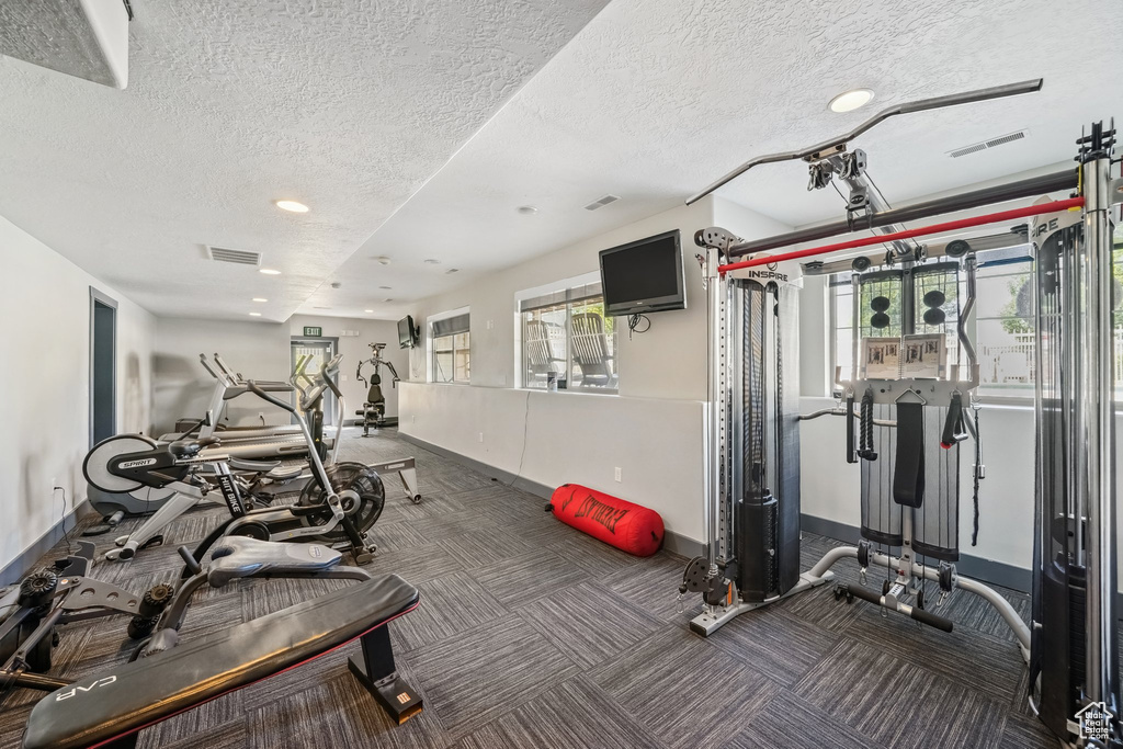 Workout area featuring baseboards, a textured ceiling, recessed lighting, and carpet flooring