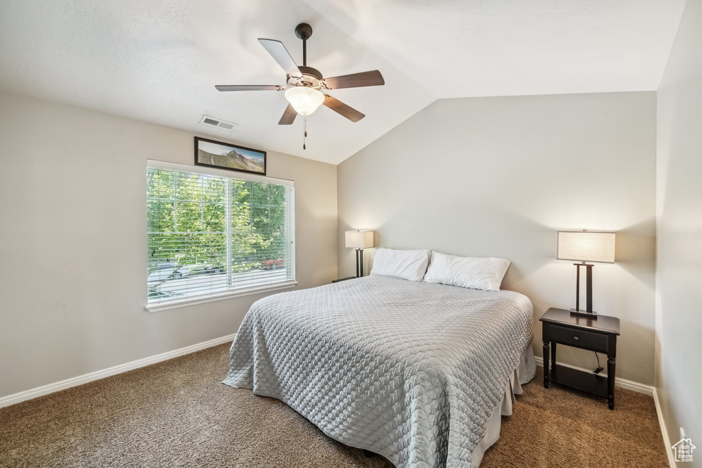 Carpeted bedroom with lofted ceiling, baseboards, and a ceiling fan