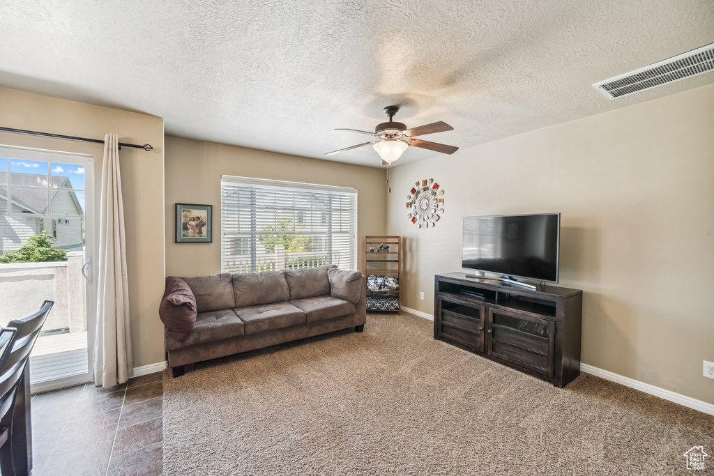 Living area with ceiling fan, baseboards, and a textured ceiling