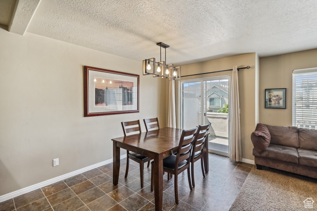 Dining room featuring a chandelier, a textured ceiling, and baseboards