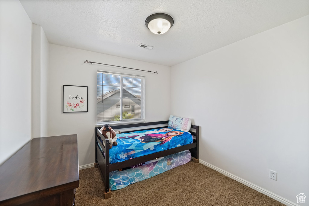 Carpeted bedroom with baseboards and a textured ceiling