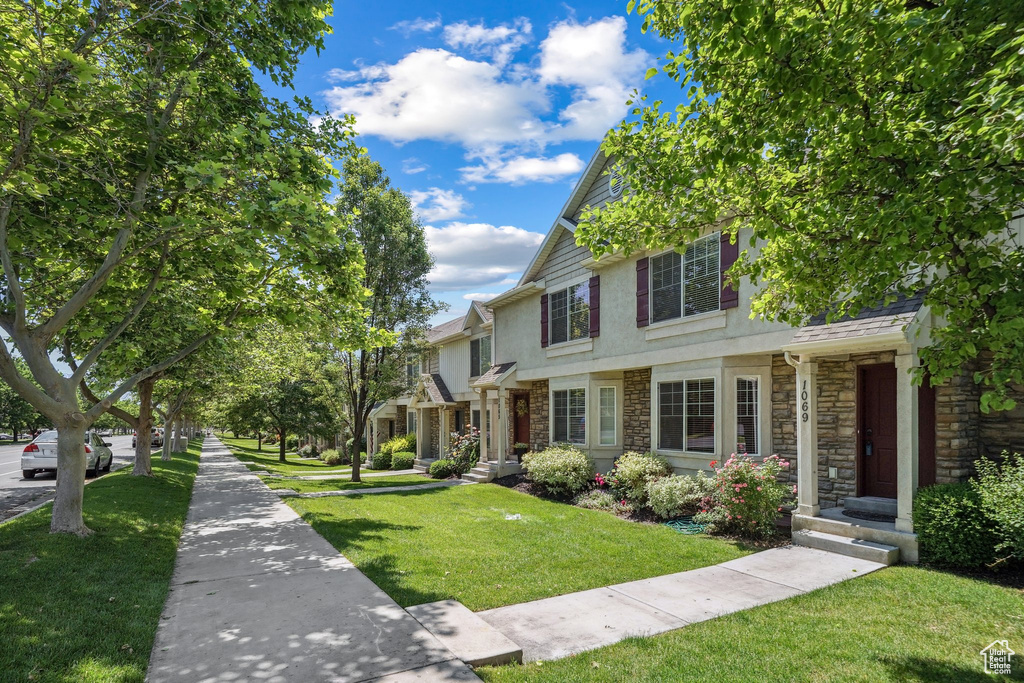 View of front facade with stone siding, stucco siding, and a front lawn
