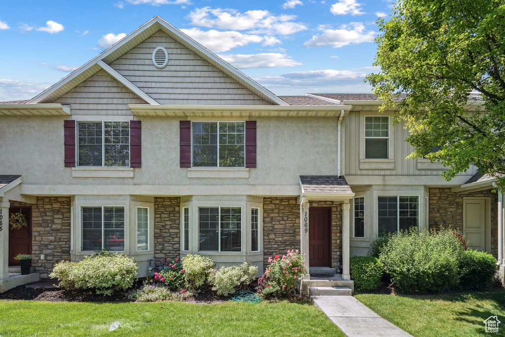Multi unit property featuring stone siding, stucco siding, and a front yard